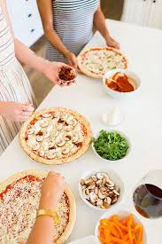 3 people making pizzas in a kitchen